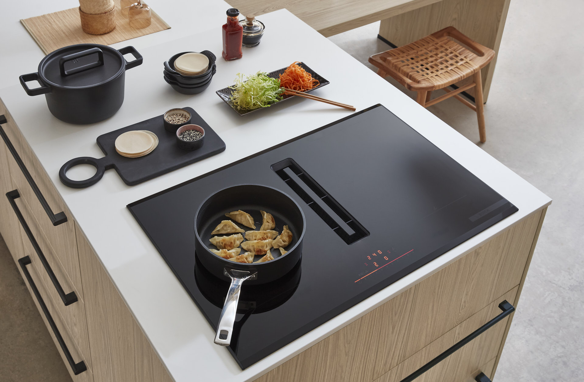 Induktionskochfeld von Bosch auf einer Kücheninsel, Matt weiße Inseloberfläche und Eichenfronten