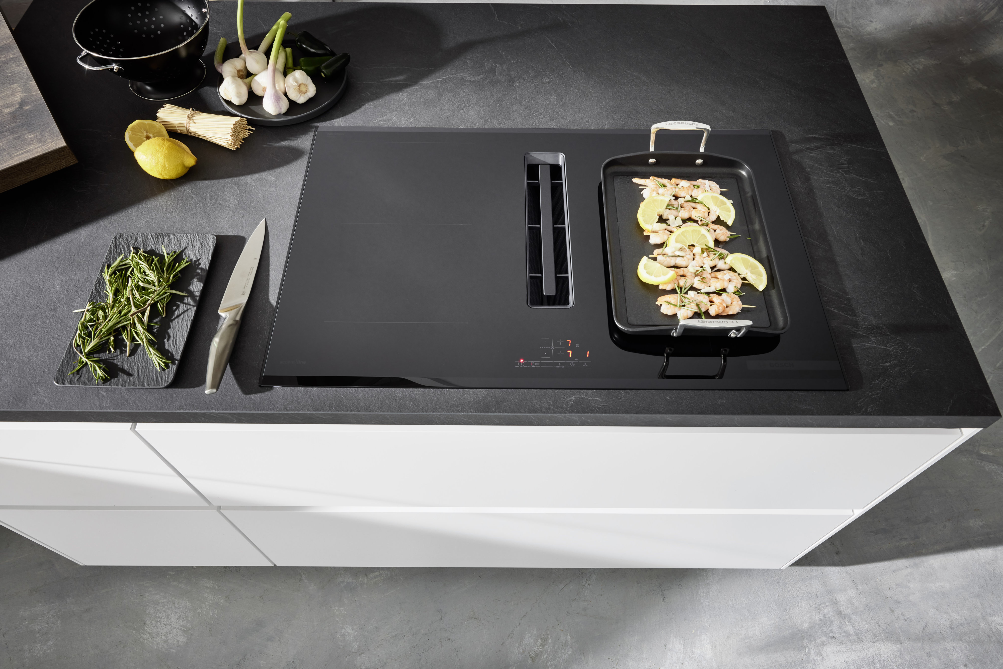 Schwarzweiße Kochinsel weiße grifflose Fronten APL Schiefer-Optik mattschwarzes Kochfeld mit Muldenlüfter