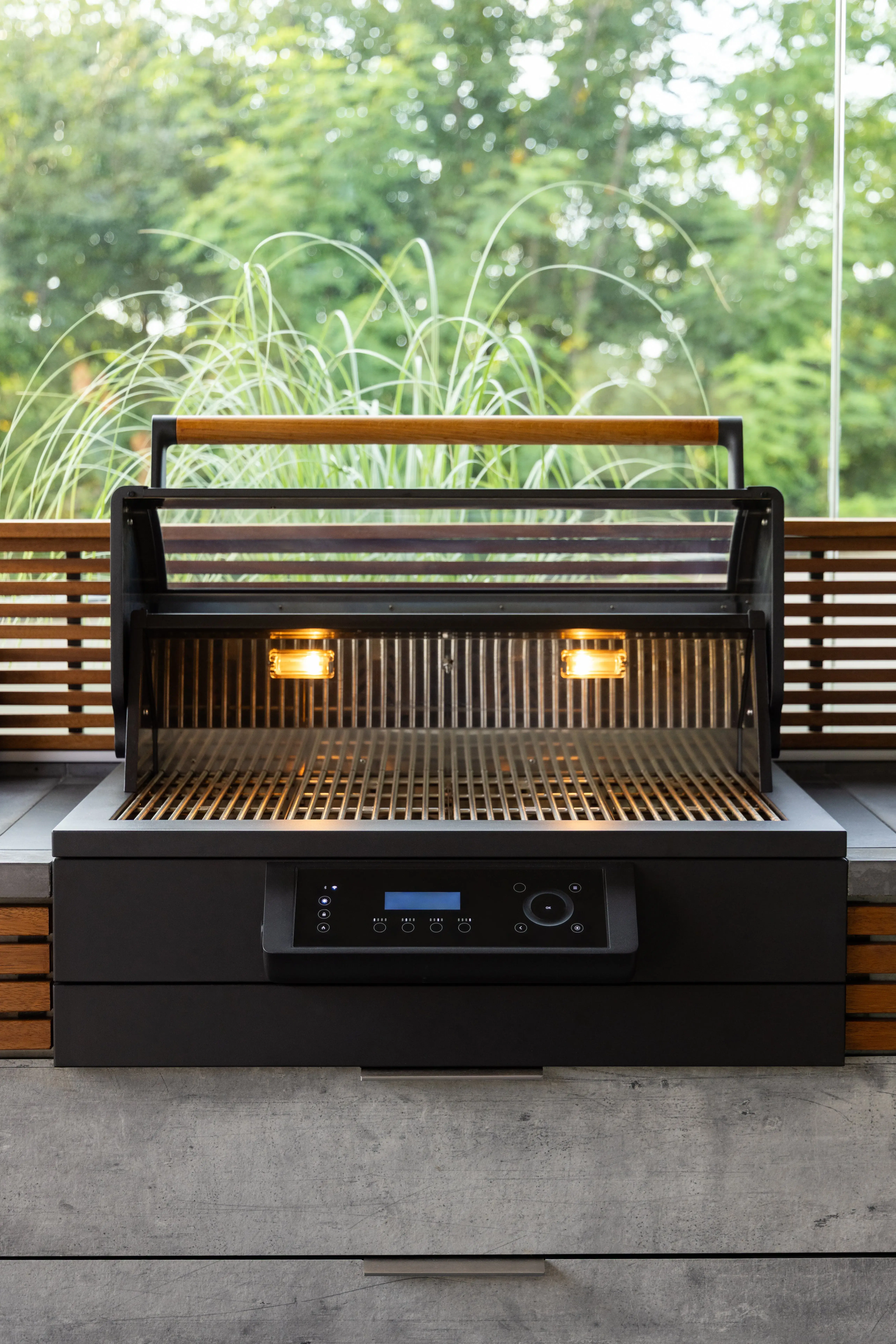 Moderner Grill mit geöffnetem Deckel und eingeschalteter Innenbeleuchtung.